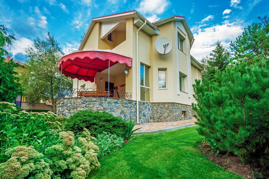 Custom built home with a lush green yard and blue sky above.