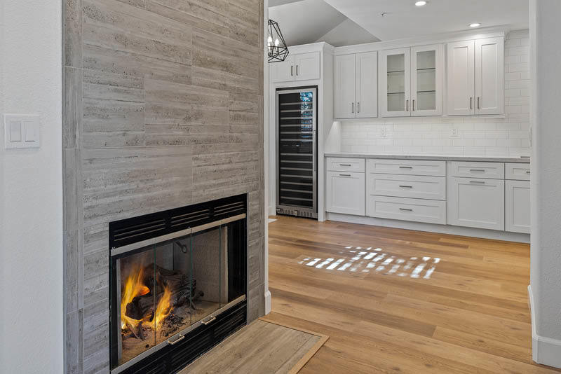 Remodeled Kitchen Interior with gray tile, fireplace and white kitchen