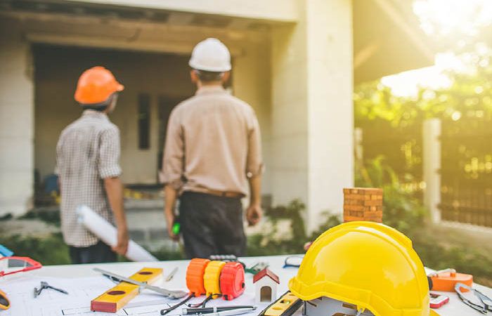 Contractors with tools in backdrop observing house