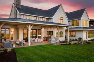 Gorgeous Farmhouse style home at sunset with covered porch and Gable roof.