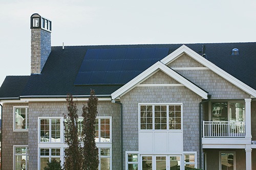 A beautiful modern home with solar power panels installed on the roof