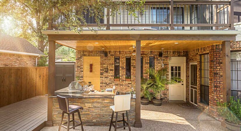 covered outdoor kitchen in brick with bar and two stools