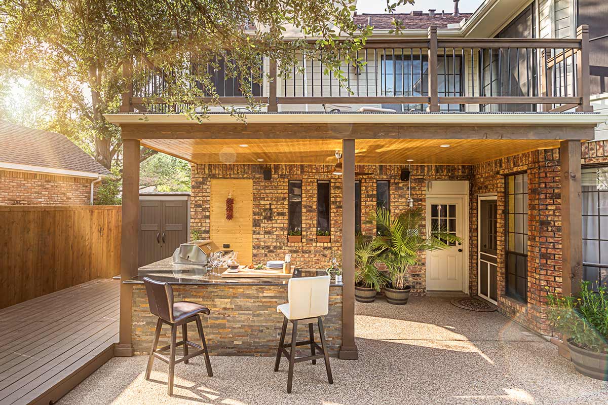 covered outdoor kitchen in brick with bar and two stools