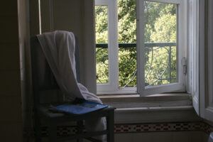 chair with towel draped on back and magazine on seat, next to open bathroom window