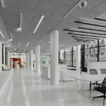 Large white room with many round white pillars and acoustic panels in parts of the ceiling.