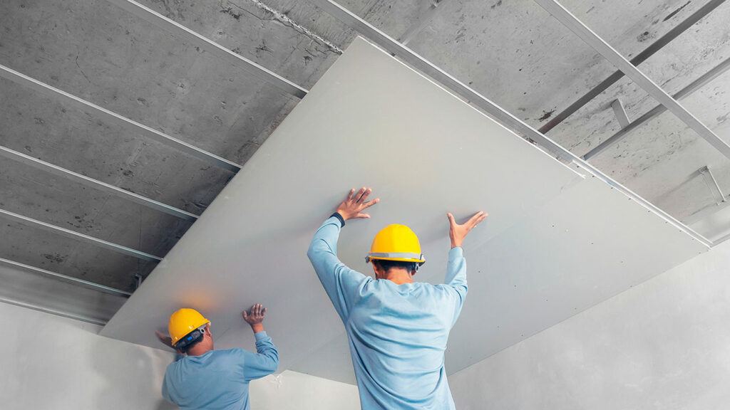 workmen placing acoustic panel in ceiling
