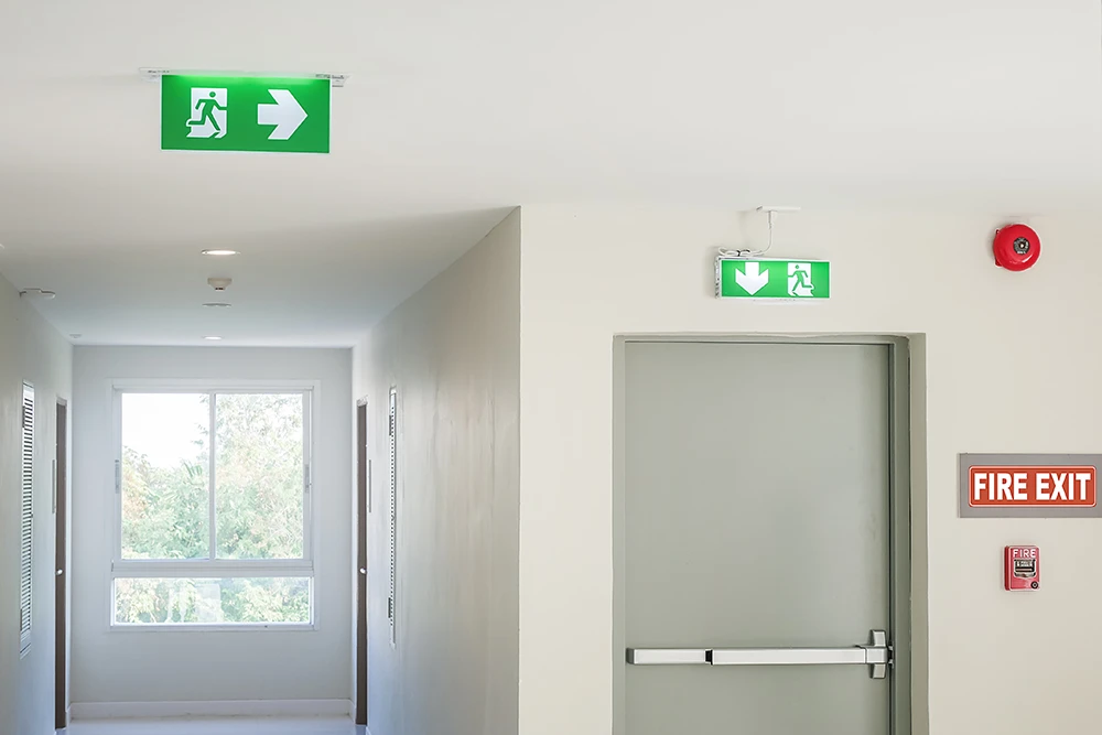 Fire exit sign and emergency signs with lights and arrows instructing how to safely exit the building in the event of an emergency