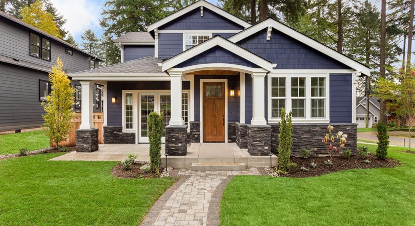 A newly constructed custom-built house with a blue exterior and a green lawn.