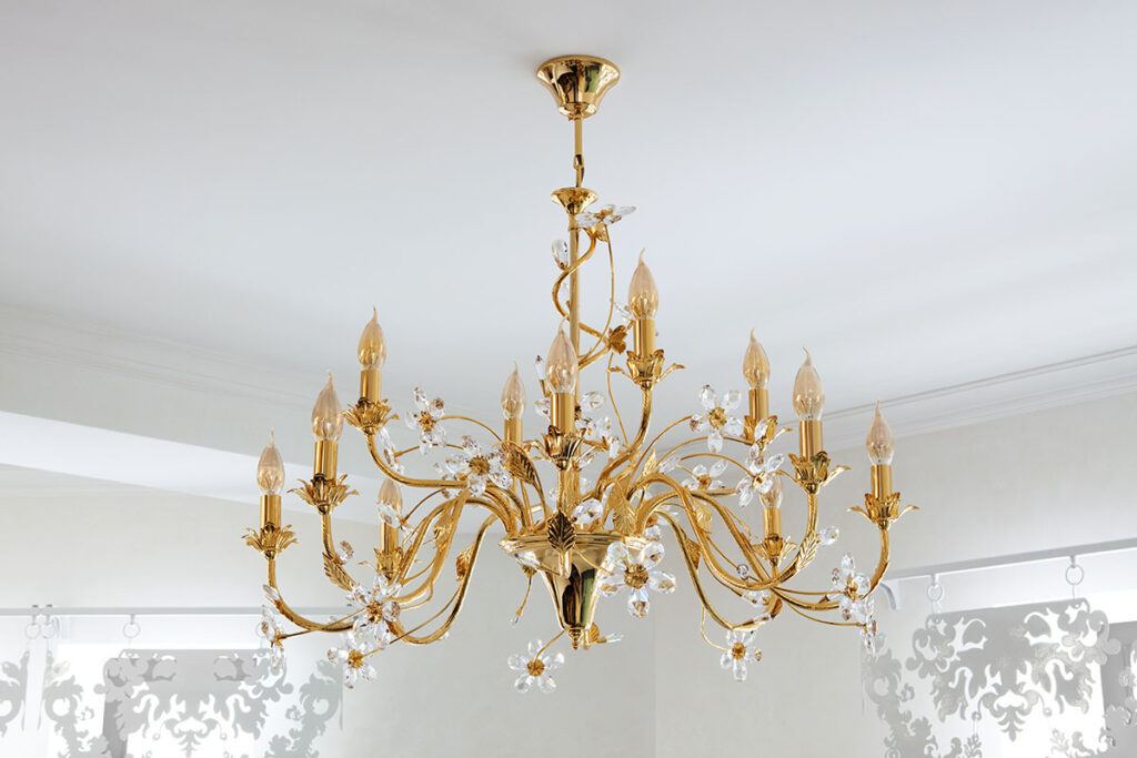 An antique historic-style brass chandelier hangs from a white ceiling in a new home build.