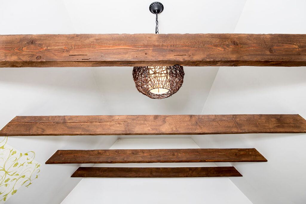 A white ceiling in a new home build features historic-style reclaimed wooden ceiling beams.