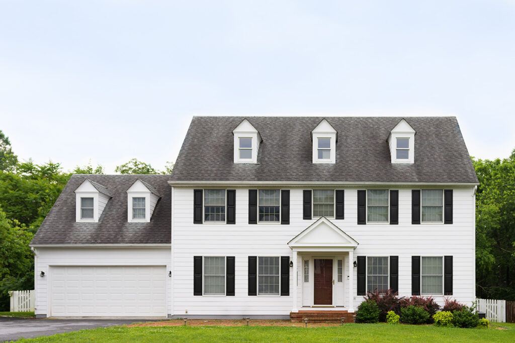 A historic style colonial home with a white exterior and large front lawn