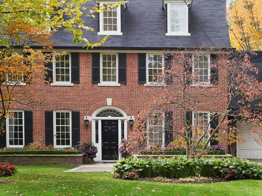 A Georgian style home with a brick exterior and black doors.