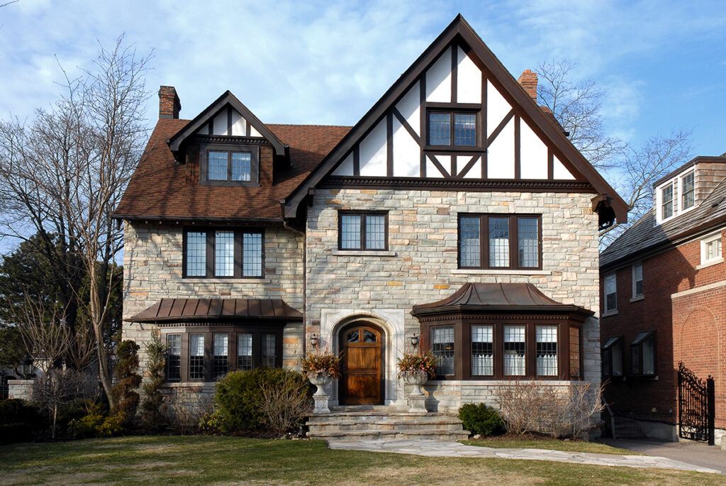 Large house with tudor-style architectural design, with bay window against a blue sky