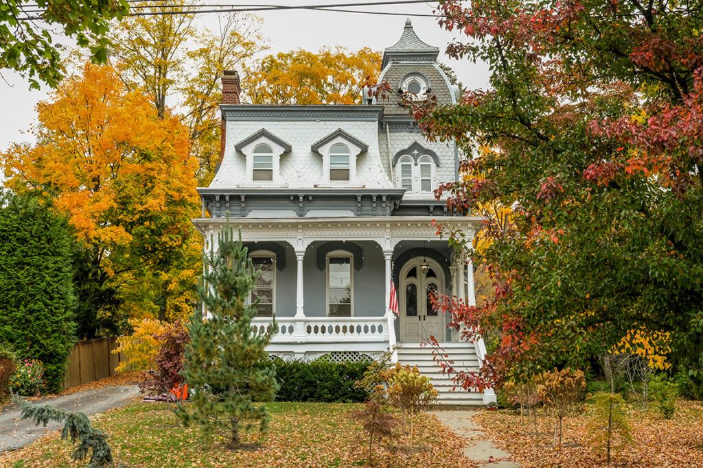 A home with Victorain style architectural design, surrounded by autumn trees.
