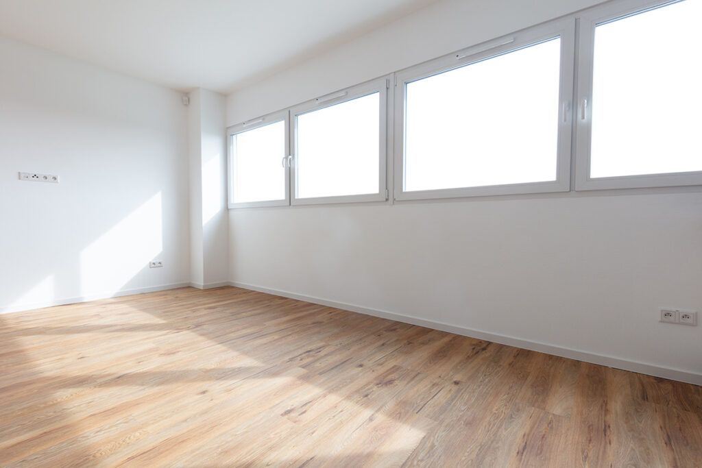 An empty and spacious newly remodeled commercial office, with white walls and natural hardwood floors.