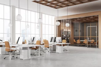 A spacious office building with white floors, desks, and bright windows.