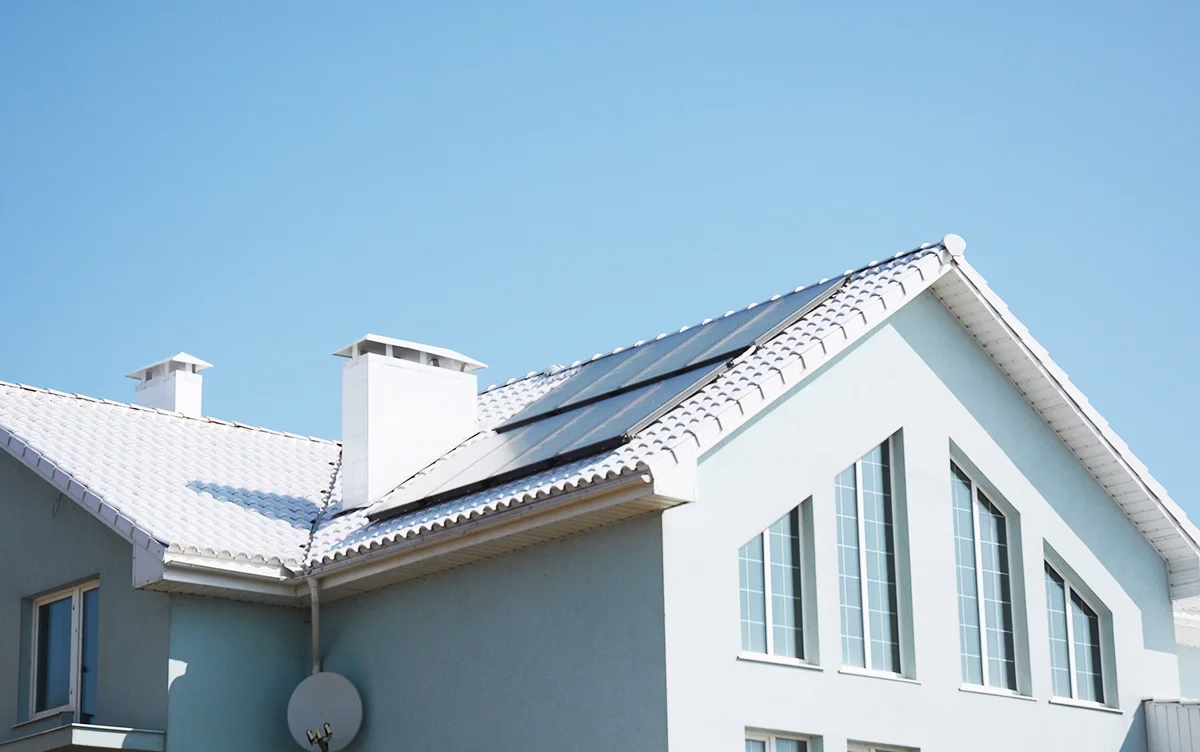 A light green house with a white reflective cool roof for energy efficiency