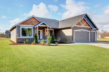 The exterior of a house with gray paint, white trim, wood accents, and a large front lawn, showing the concept of whether it's better to remodel or buy a new home