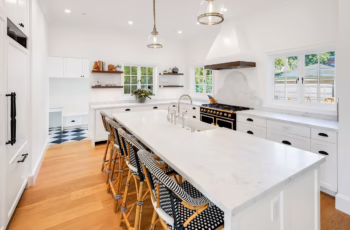 The interior of a newly renovated kitchen with white countertops and hardwood floors