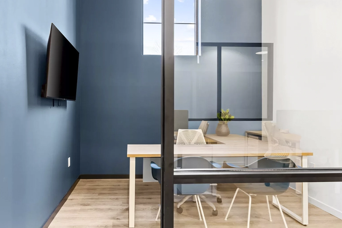 A private office in the Harper Building coworking space in Garden City, ID, with hardwood floors, blue walls, a TV, and a desk