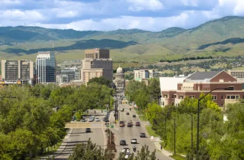 An aerial shot of downtown Boise, Idaho, in the Treasure Valley, with green trees and the Boise foothills in the background
